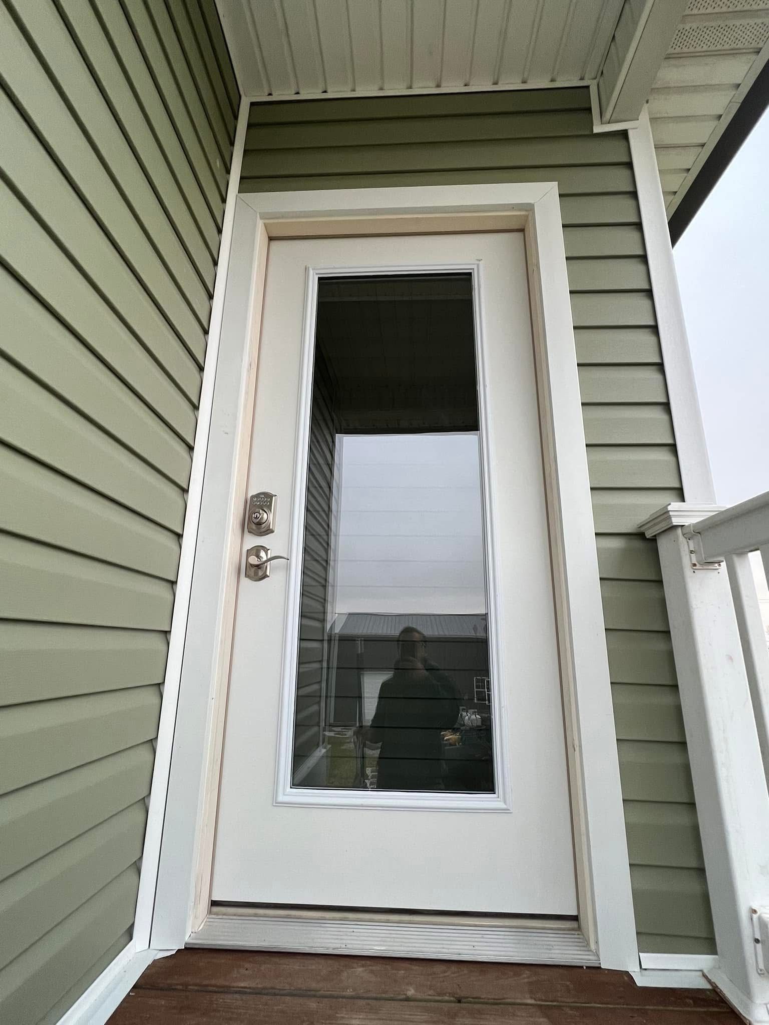 A white door with a glass window is on the side of a house.