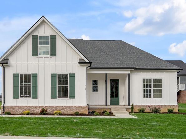 A white house with green shutters and a gray roof