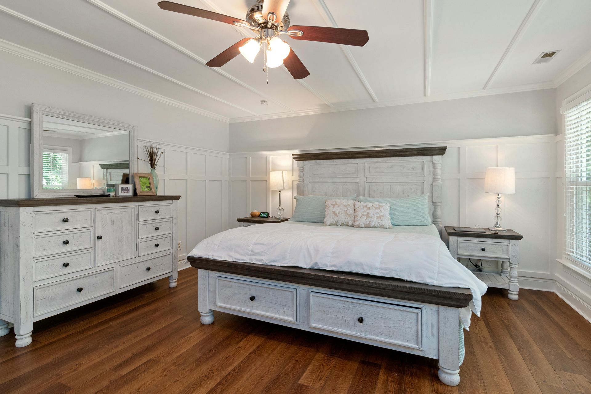 A bedroom with a bed , dresser , mirror and ceiling fan.