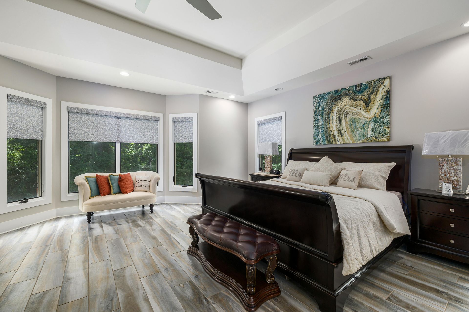 A bedroom with a sleigh bed , a bench , a couch and a painting on the wall.