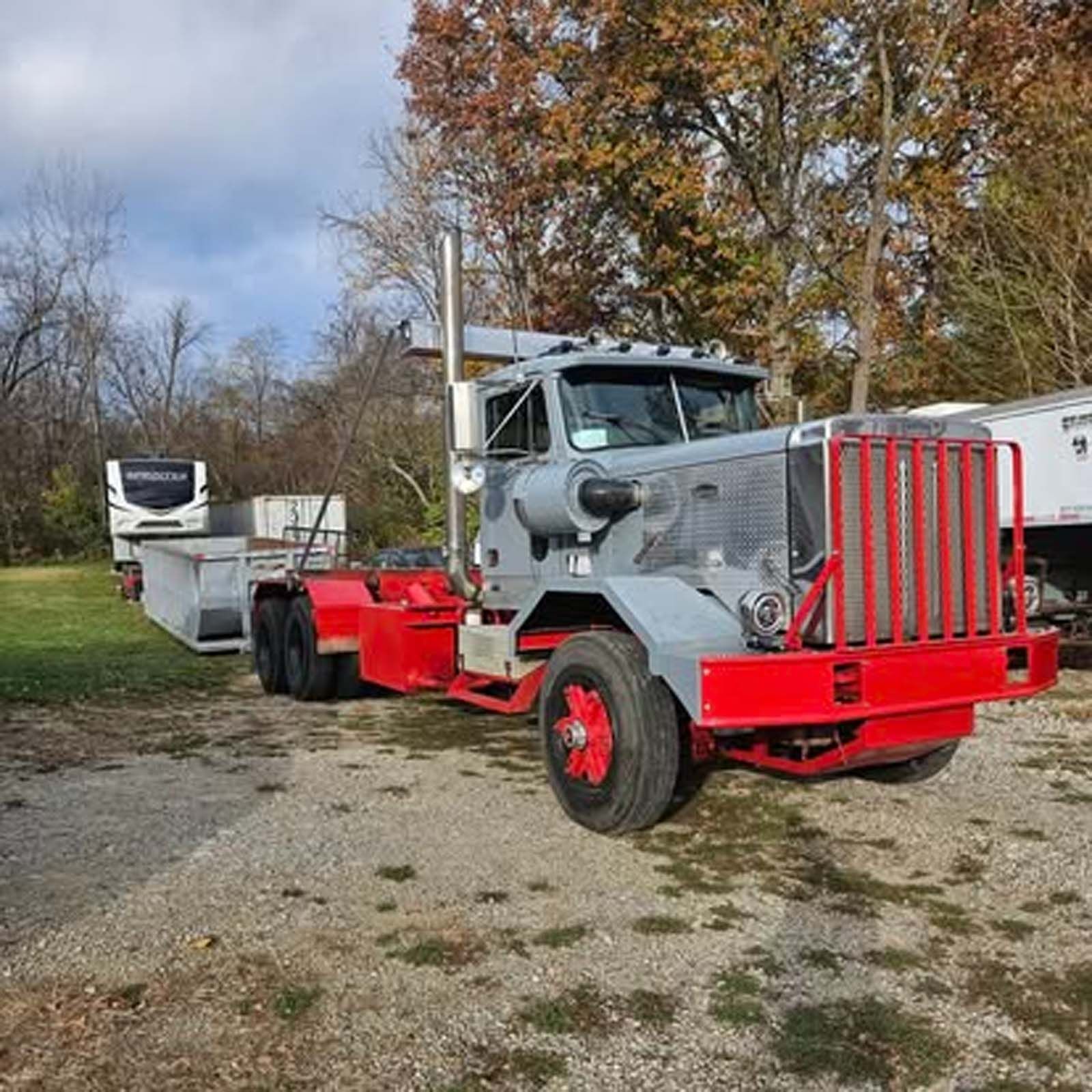 A semi truck with a trailer attached to it is parked in a gravel lot.