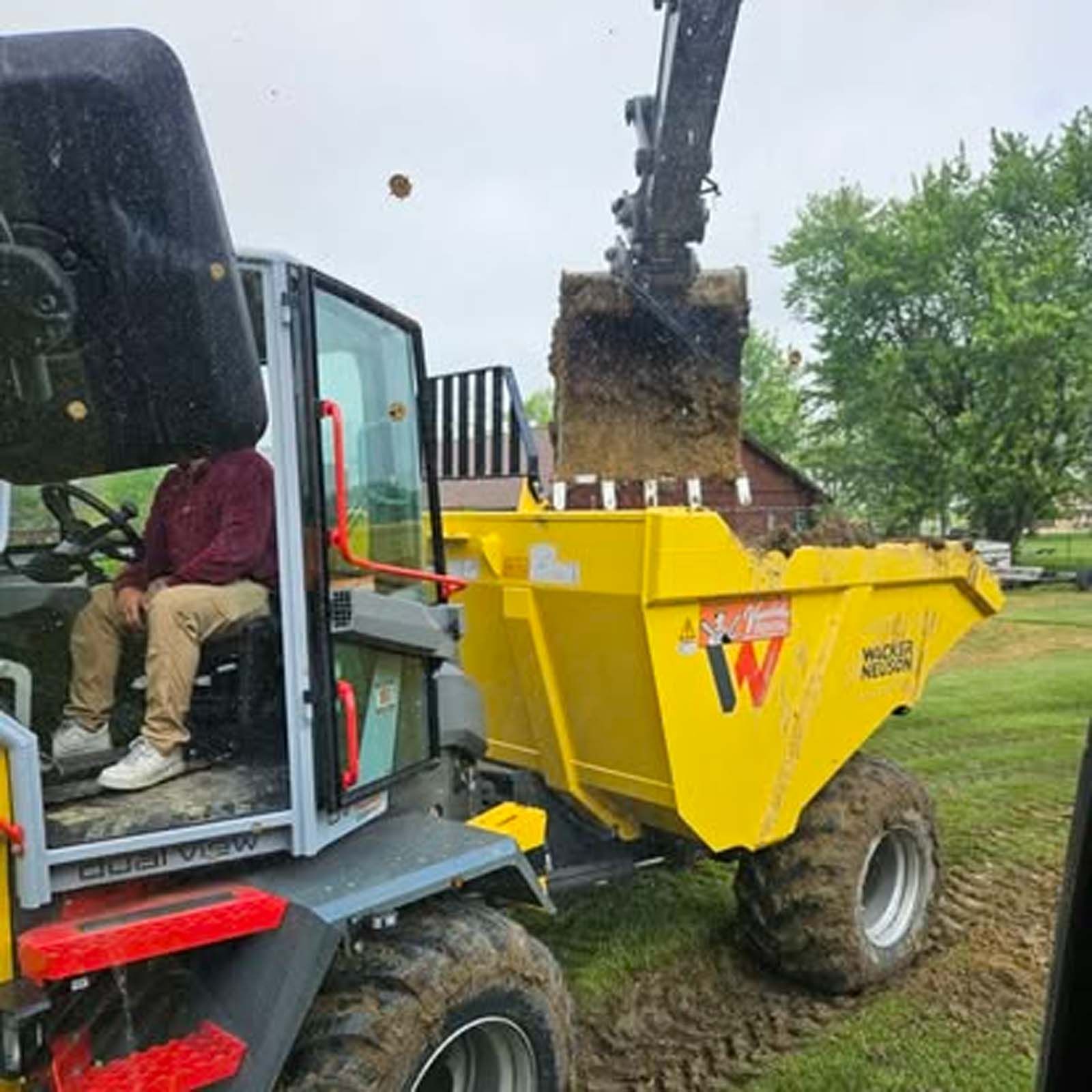 A man is sitting in the driver 's seat of a dump truck.