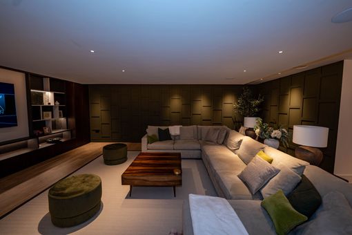 Modern living room with sectional sofa, ottomans, wooden coffee table, and warm recessed lighting