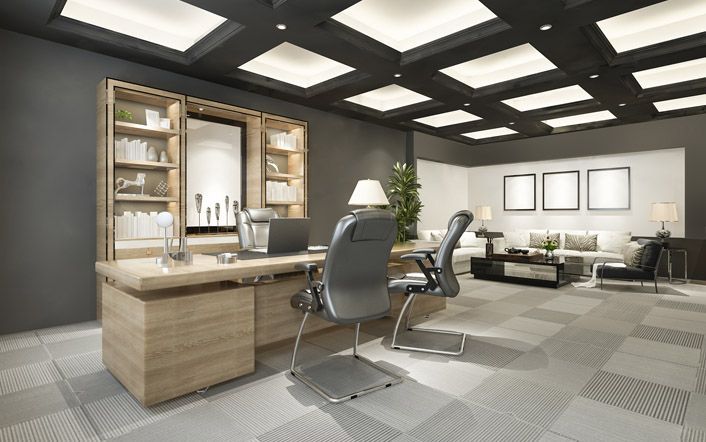 Modern office with desks, chairs, shelves, and a sitting area under bright ceiling lights