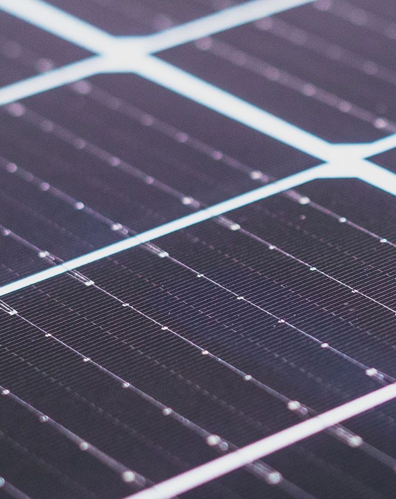 Close-up of dark solar panels with white grid lines and reflections