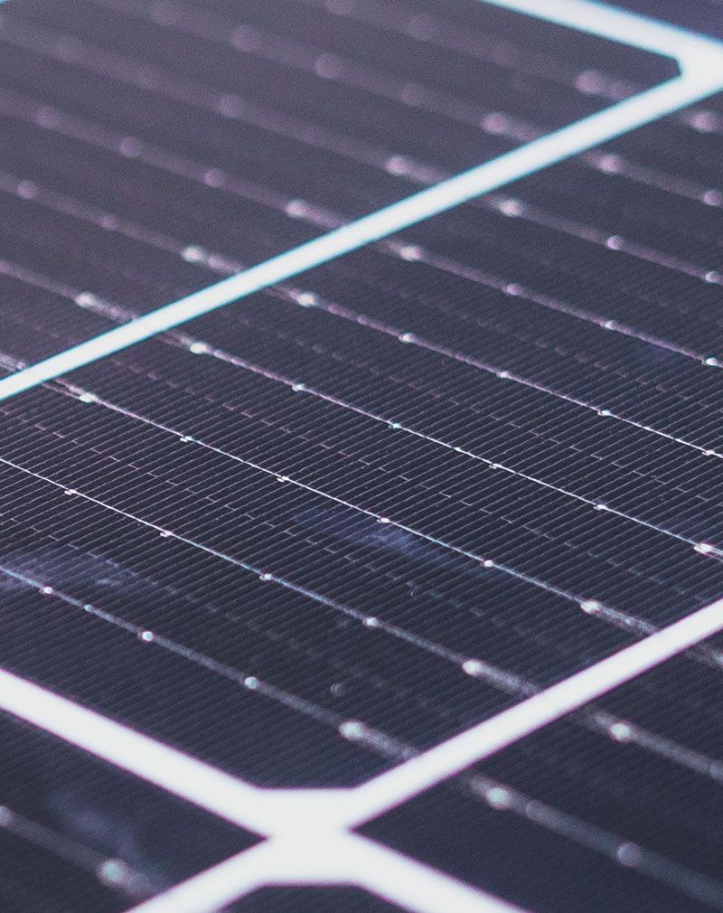 Close-up of a dark solar panel with white grid lines and dust specks.