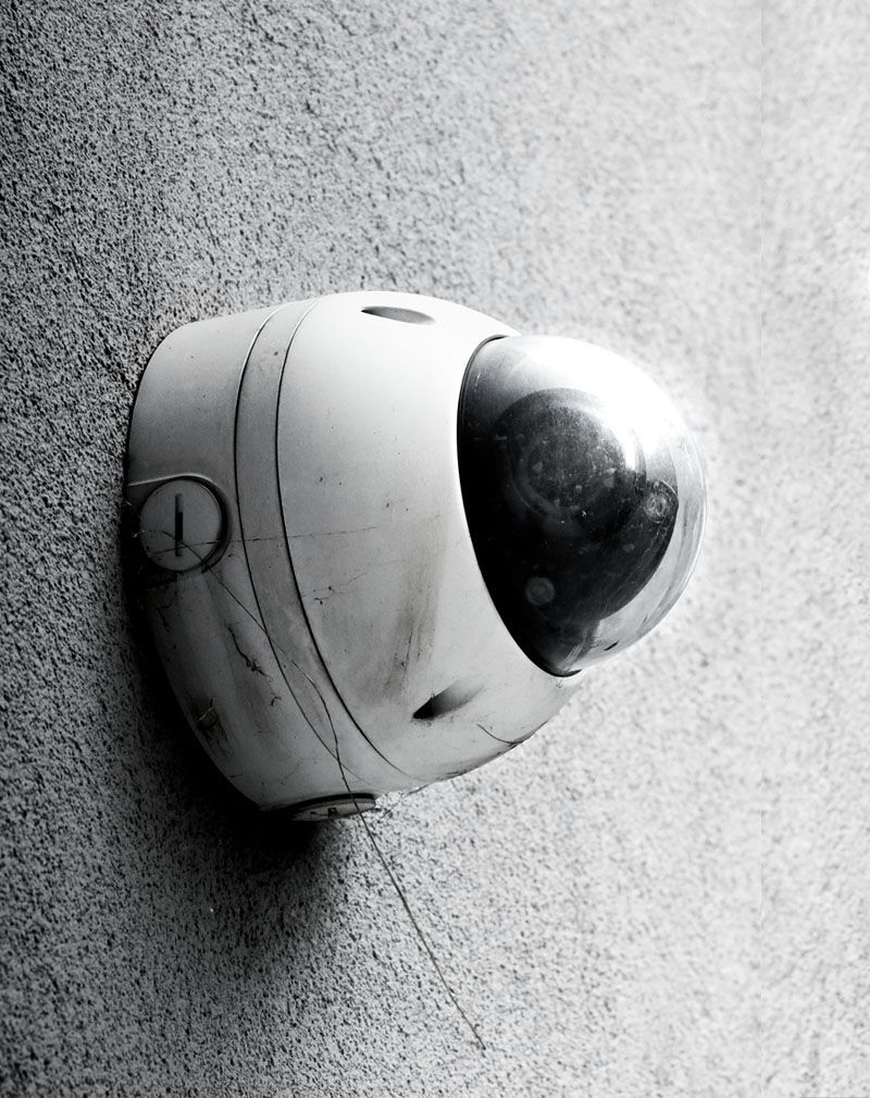 Wall-mounted security camera dome on a textured gray wall