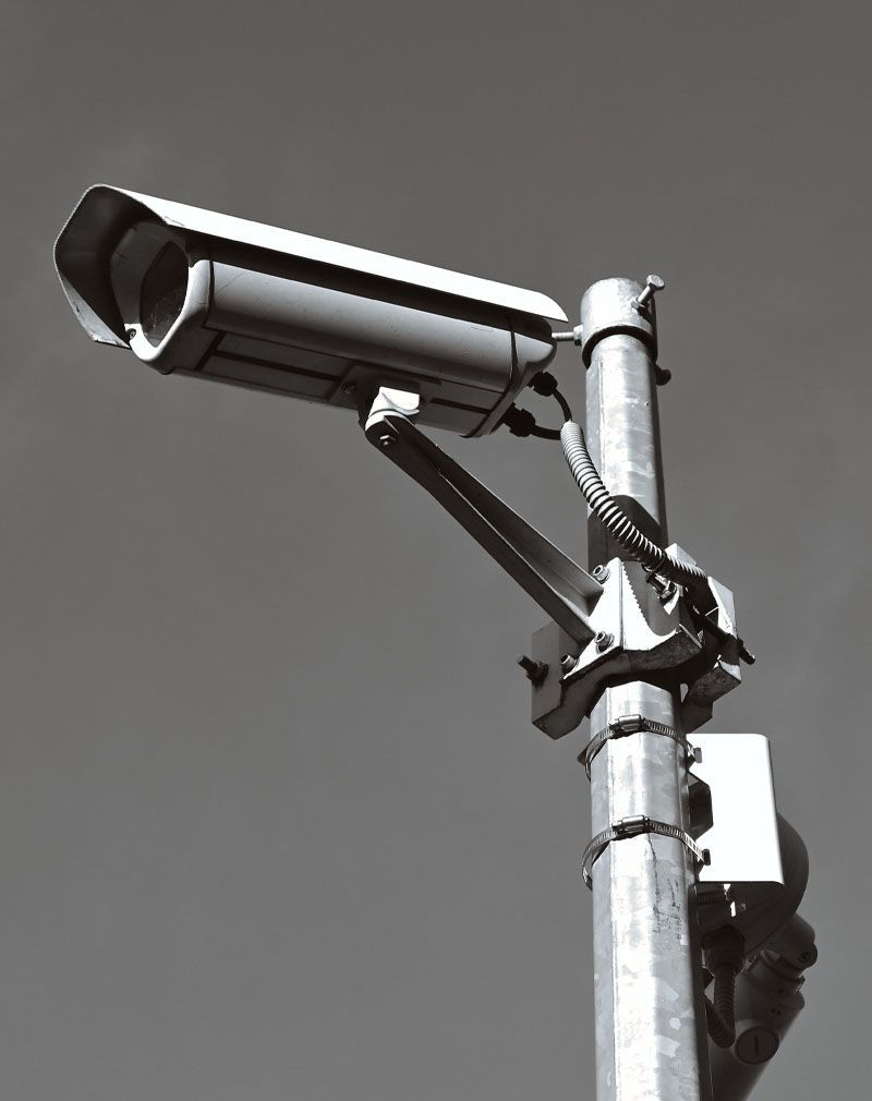 Closed-circuit security camera mounted on a pole against a gray sky