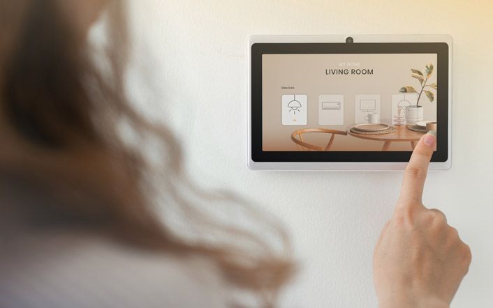 Person using a tablet to view smart home controls on a wall-mounted screen
