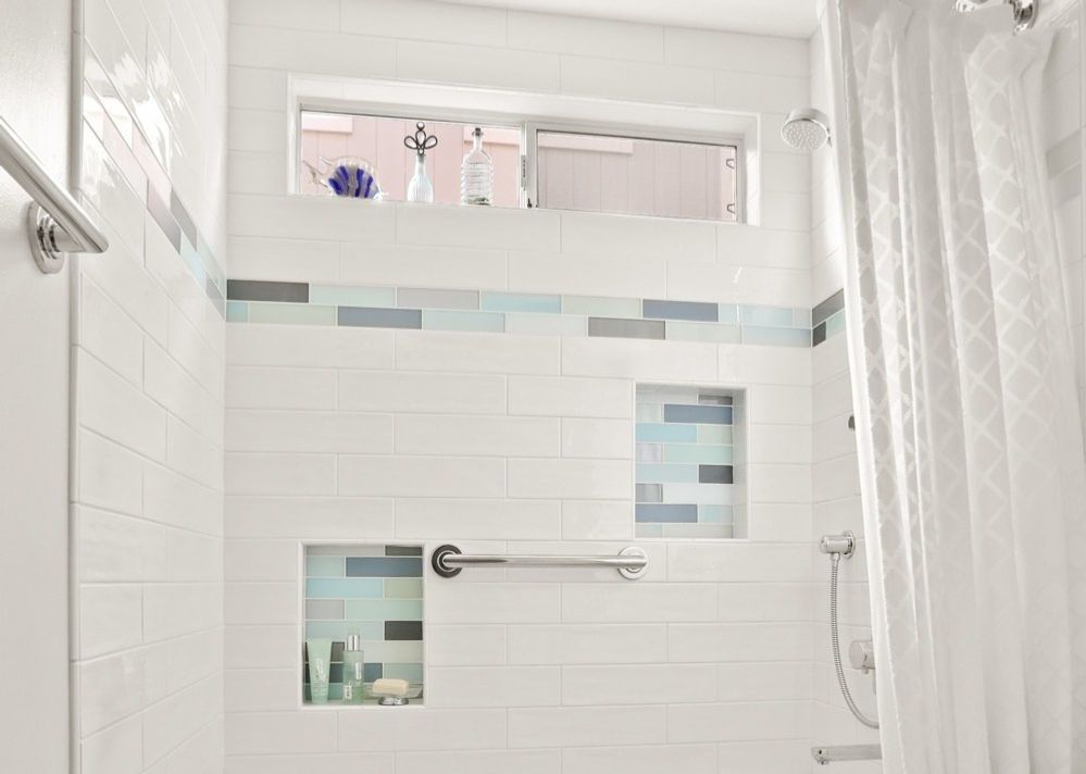 A bathroom with white tiles , a shower curtain , and a window.