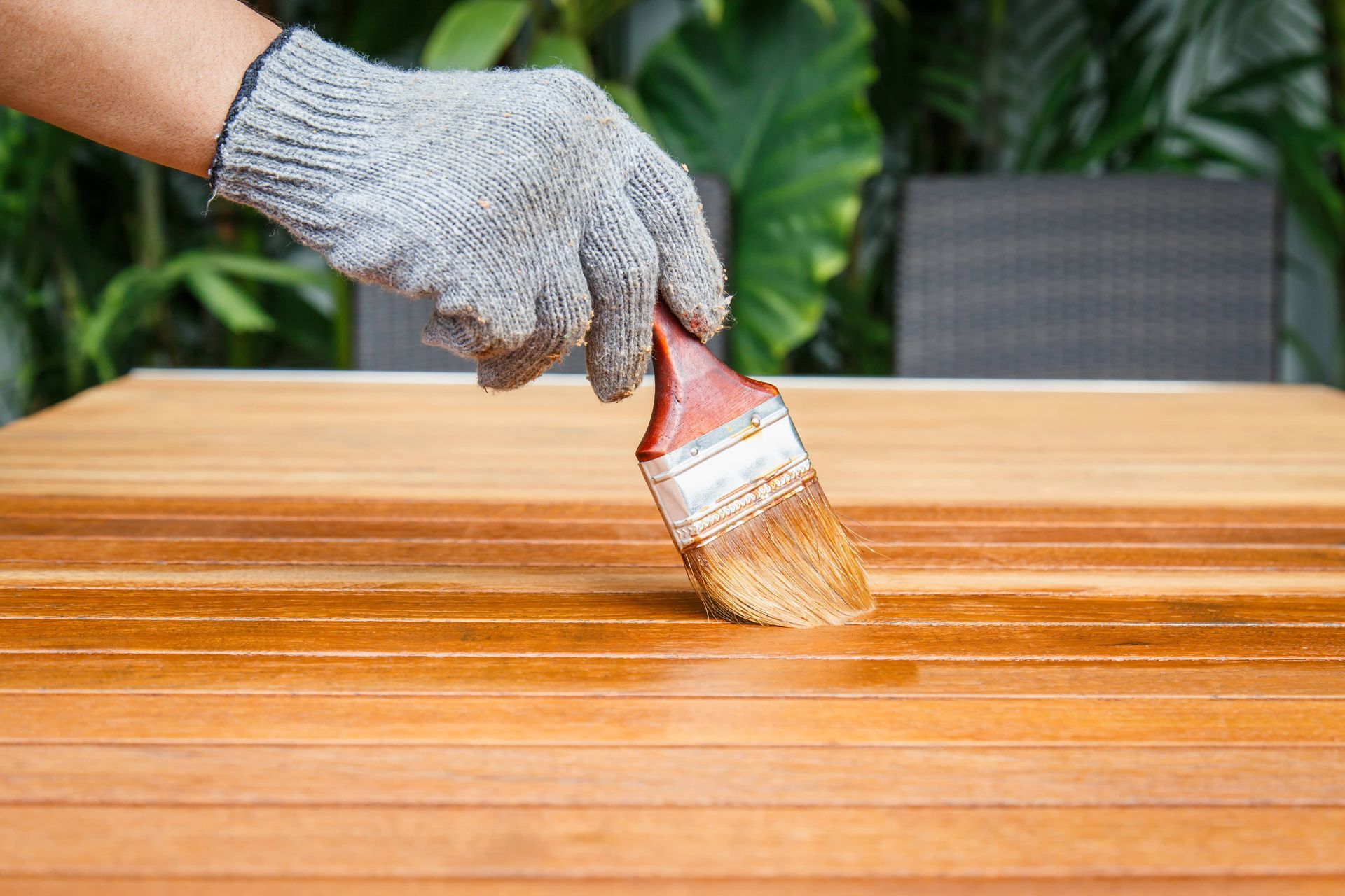 A person is painting a wooden table with a brush.