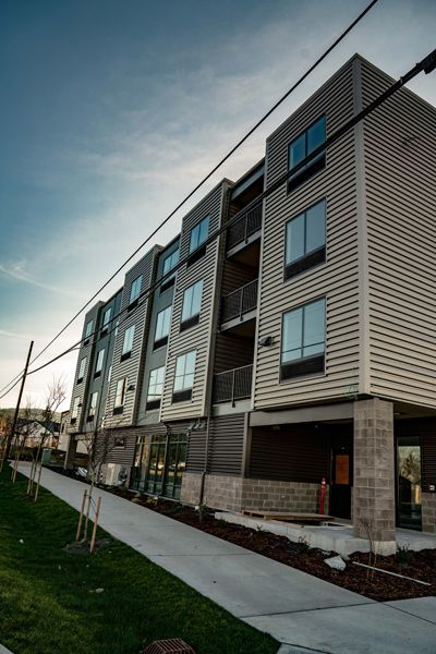 Multi-story modern building with gray siding, windows, and an accessible ramp. Power lines overhead.