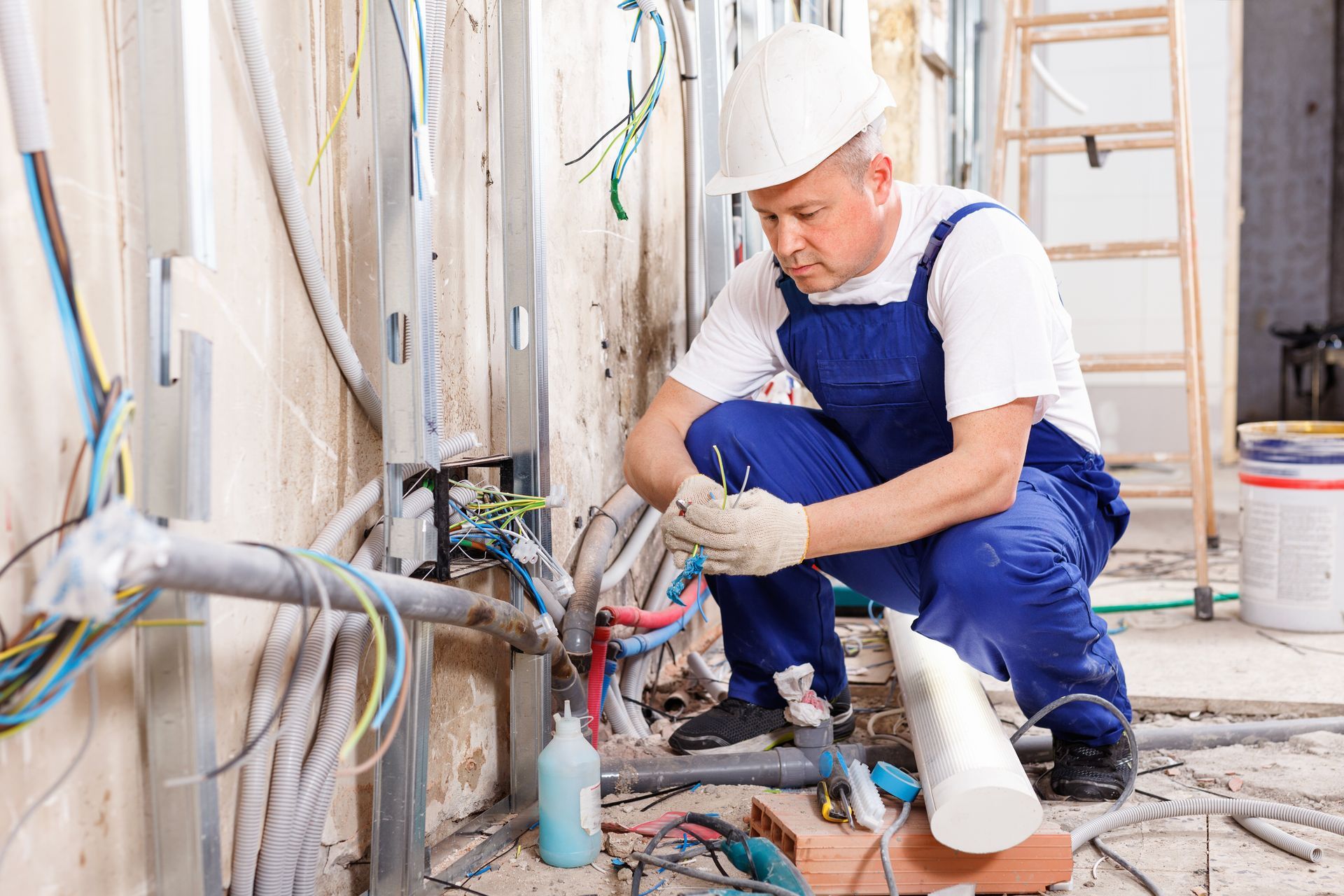 An experienced electrician laying electric wires in a building under construction.