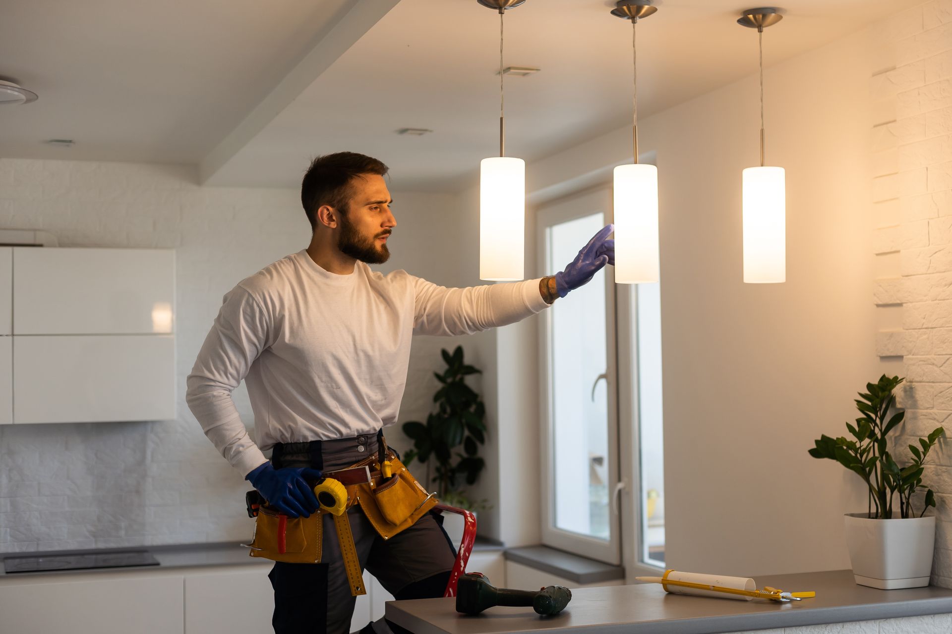 Electrician worker man assembling electric lamps in new apartment.