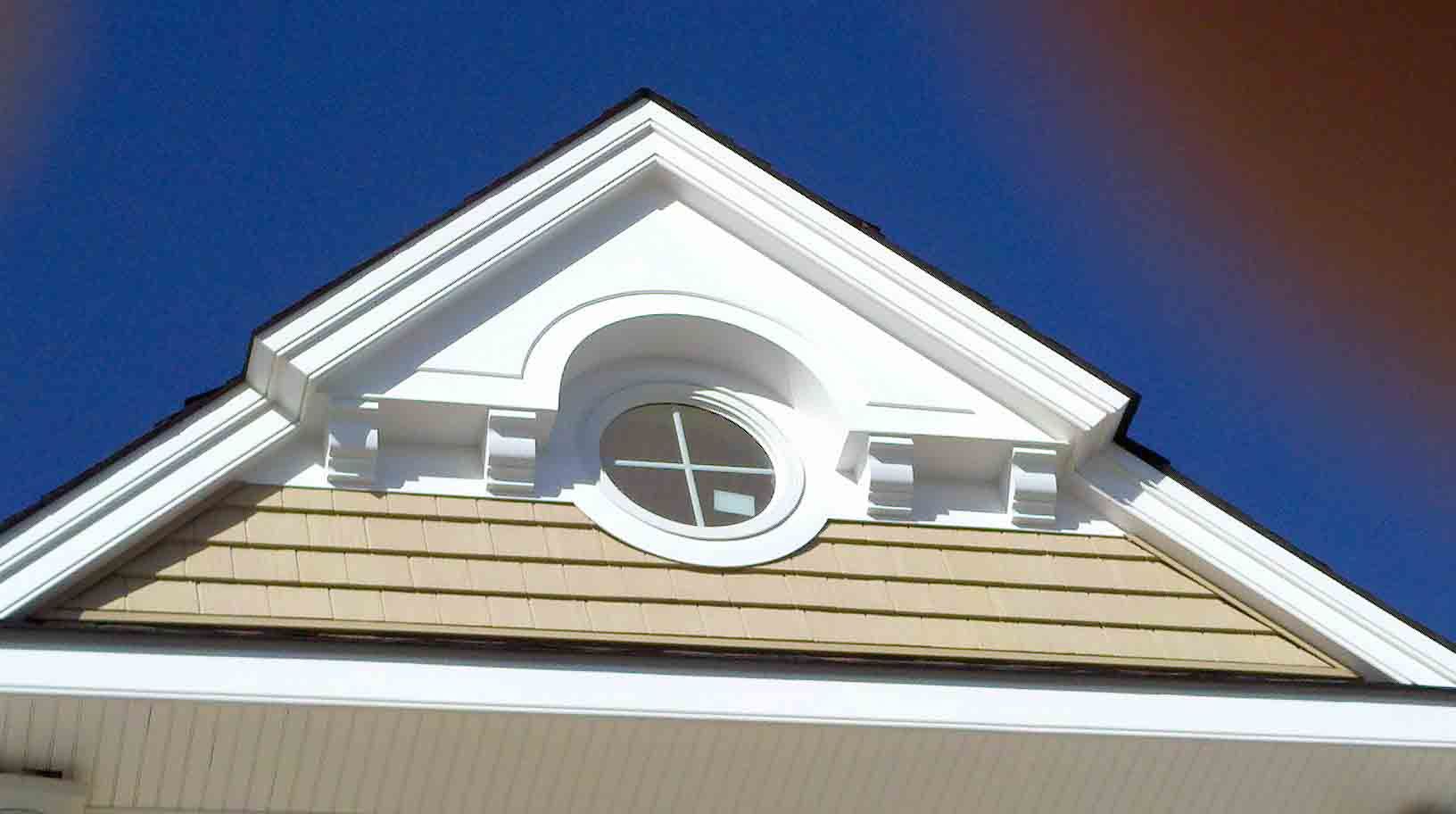 The roof of a house has a triangle with a window on it