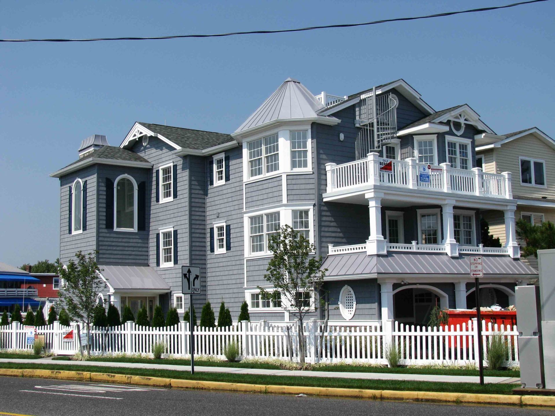 A large grey house with a white picket fence in front of it