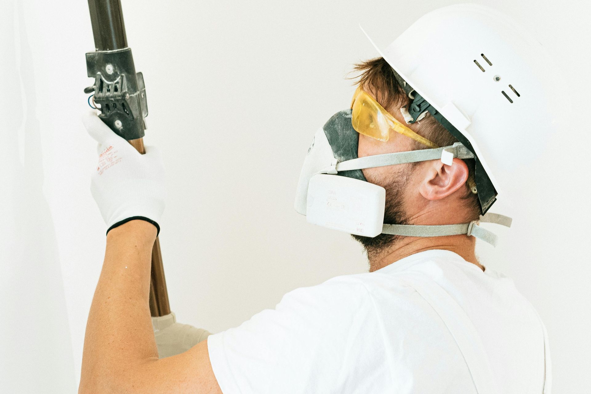 A man wearing a helmet , goggles and a mask is working on a pipe in woodfin NC