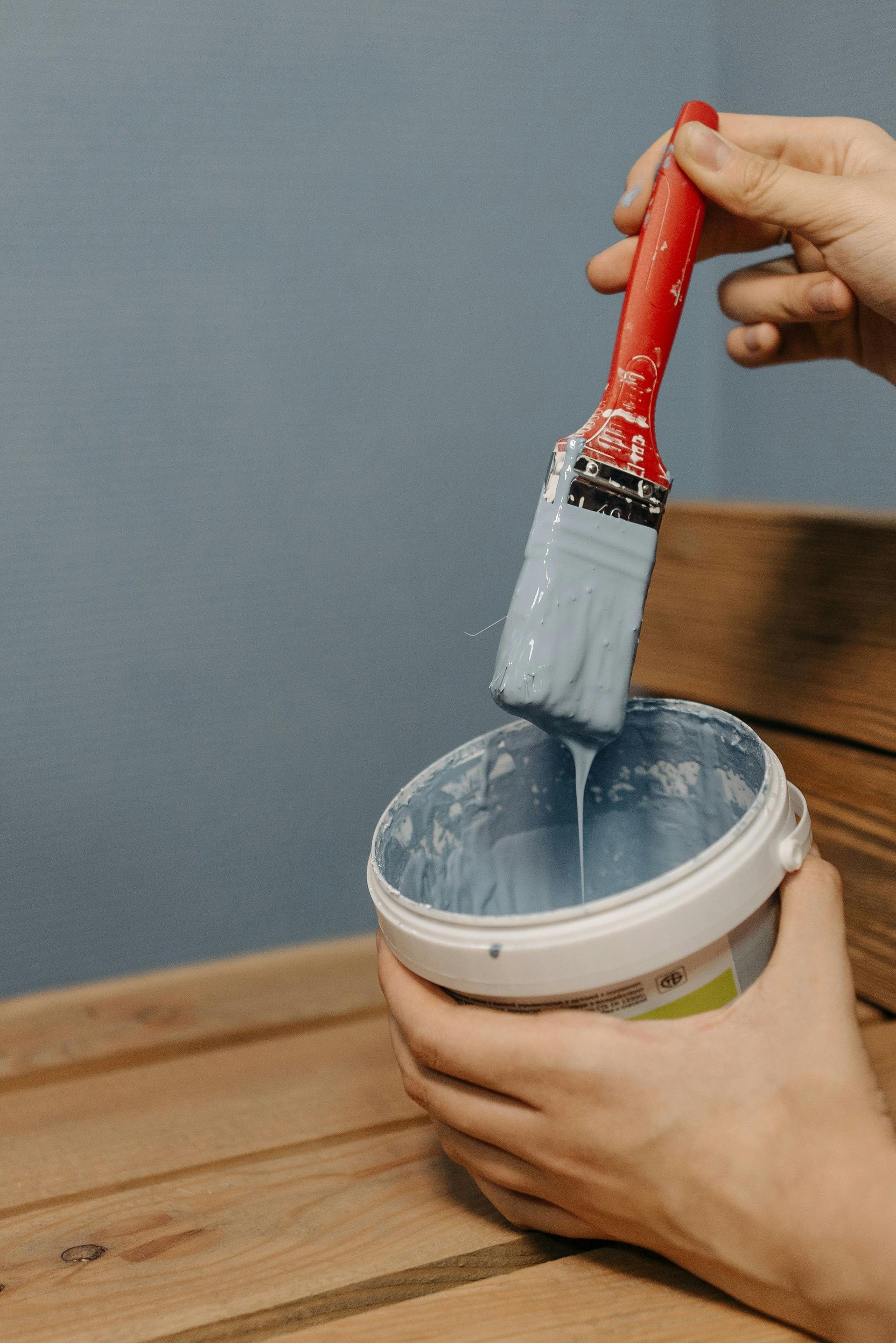 A person is holding a bucket of paint and a brush in Asheville NC