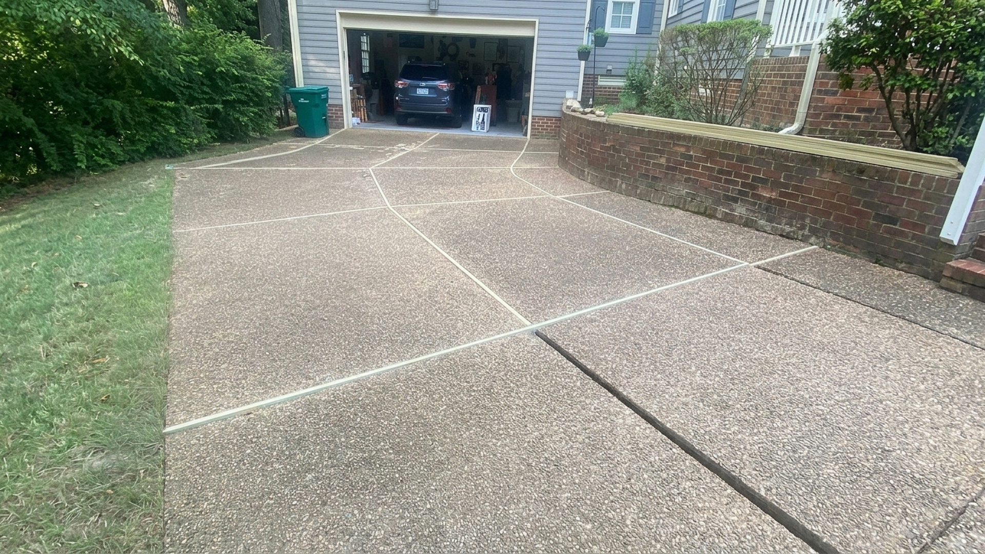 Concrete driveway leading to a garage, with grass on the left and a brick wall on the right, restoration project by Rite-Wash