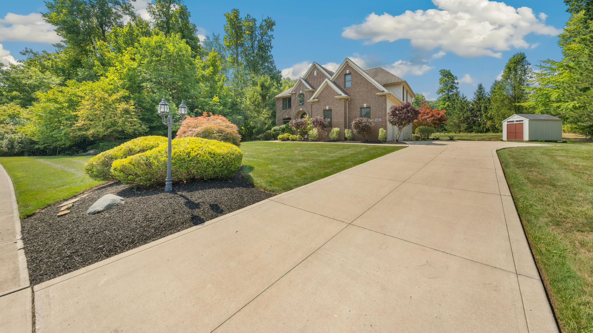 Suburban house with a long driveway, landscaped front yard, and clear blue sky