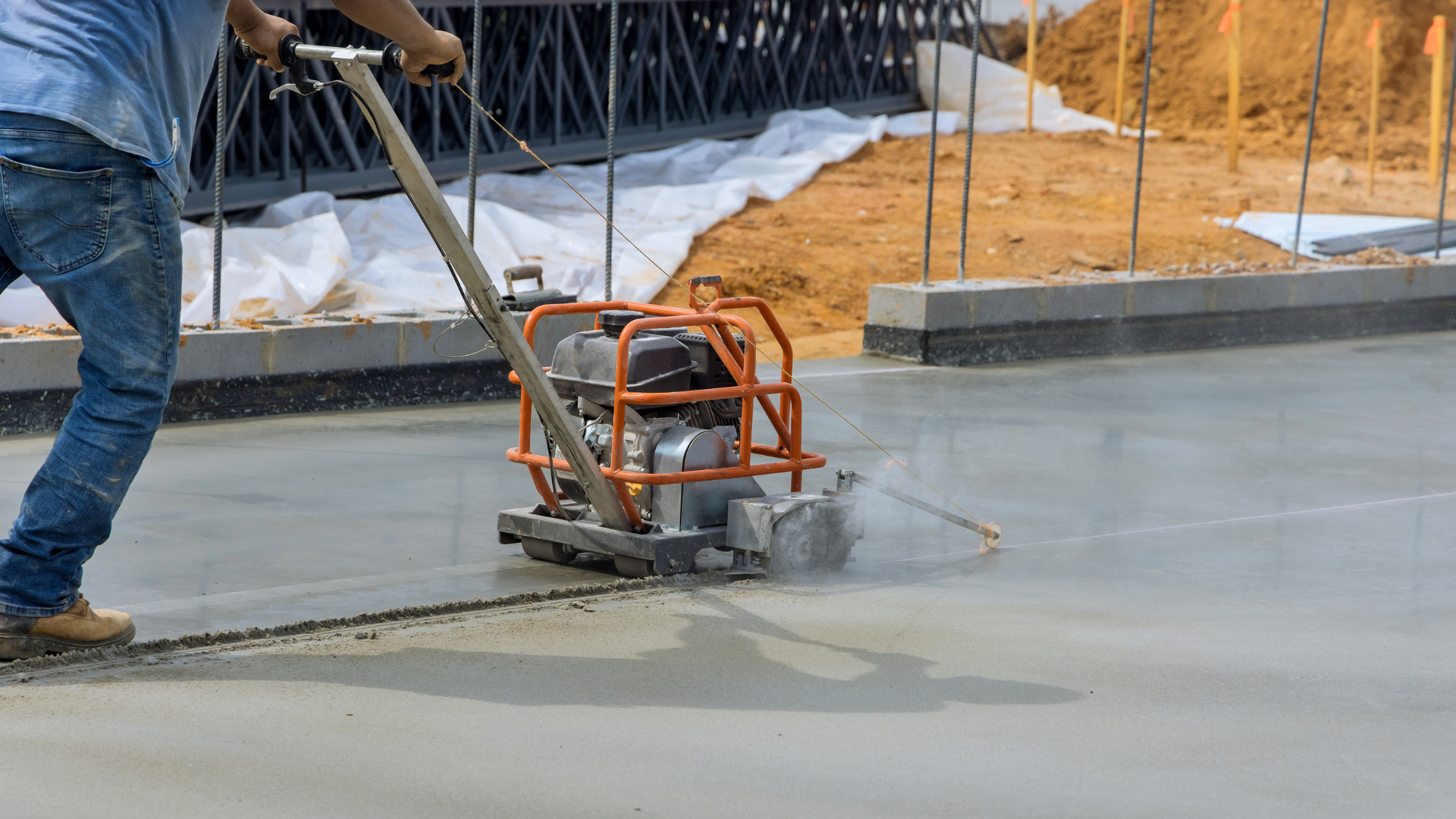 Worker operating a concrete trowel on a freshly poured slab at a construction site