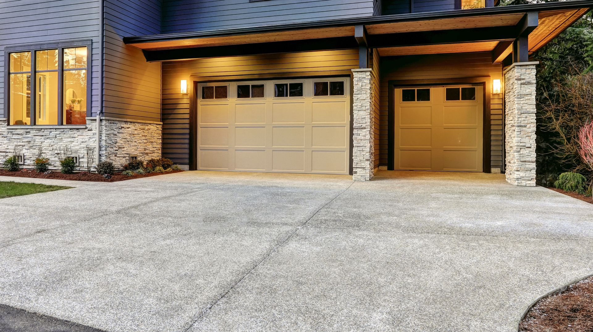 Beige garage doors under a covered entrance, with a concrete driveway and house exterior.