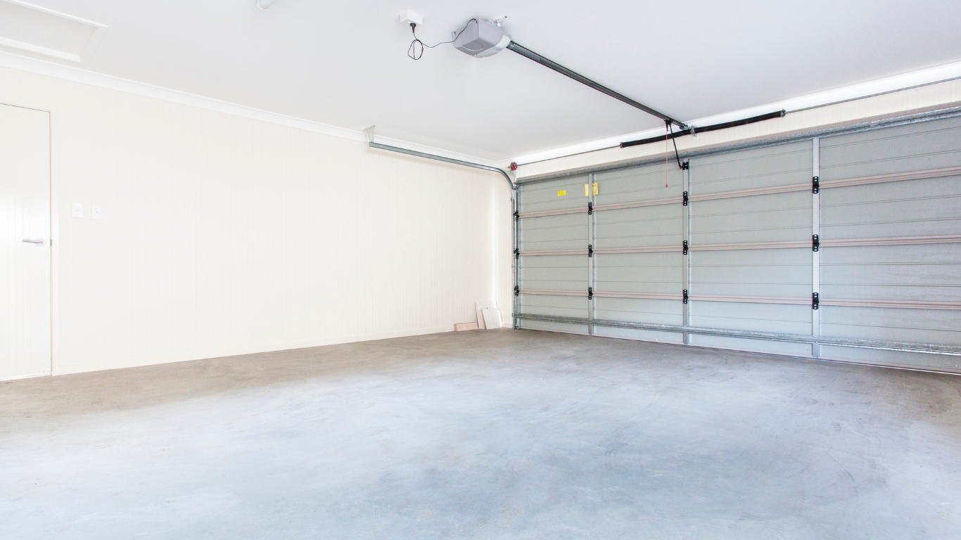 Empty white garage interior with closed overhead door and concrete floor