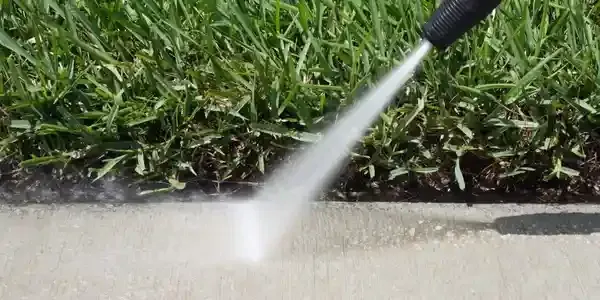 A person is cleaning a gutter with a high pressure washer.