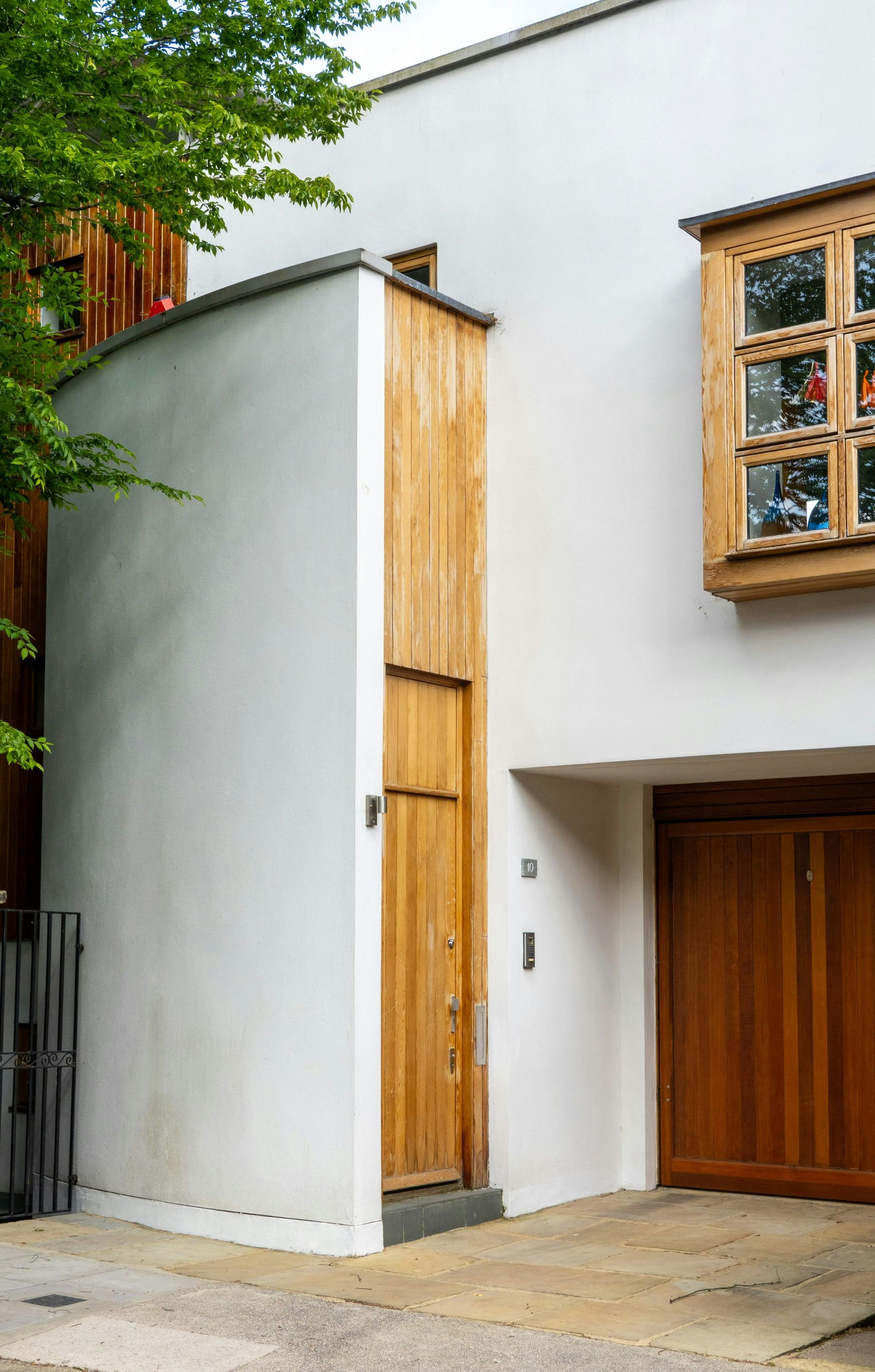 White and wood modern building with door and garage; trees in background.
