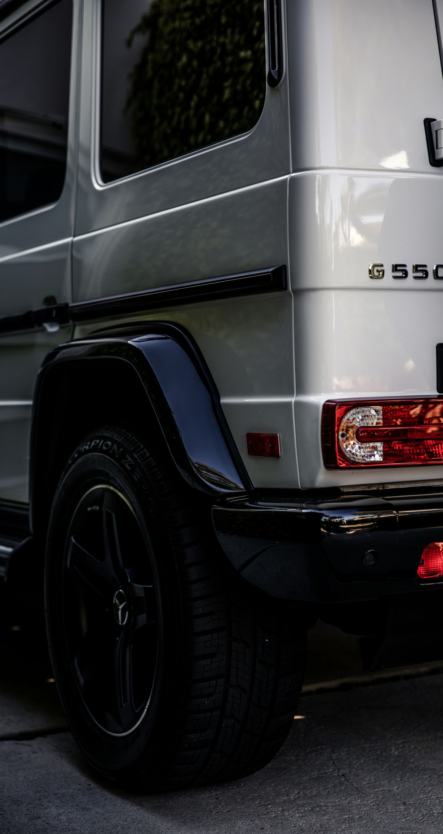 Silver Mercedes-Benz G550 SUV, black wheel and fender. Tail light visible.