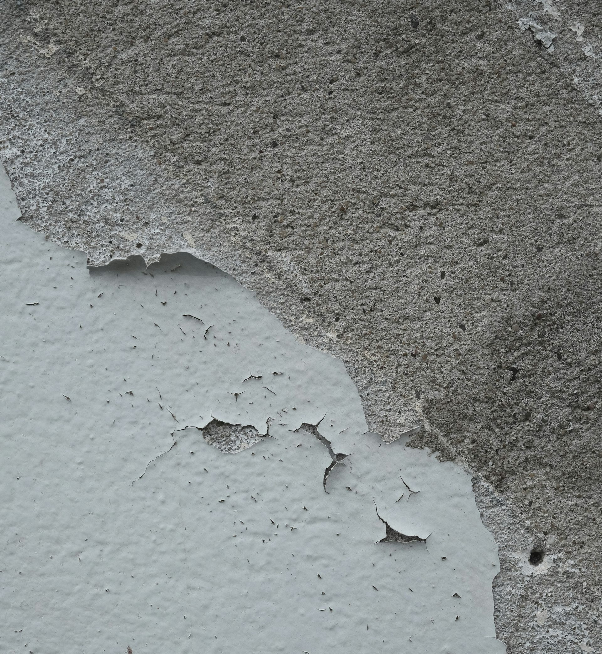 Peeling gray wall paint exposing a lighter layer beneath