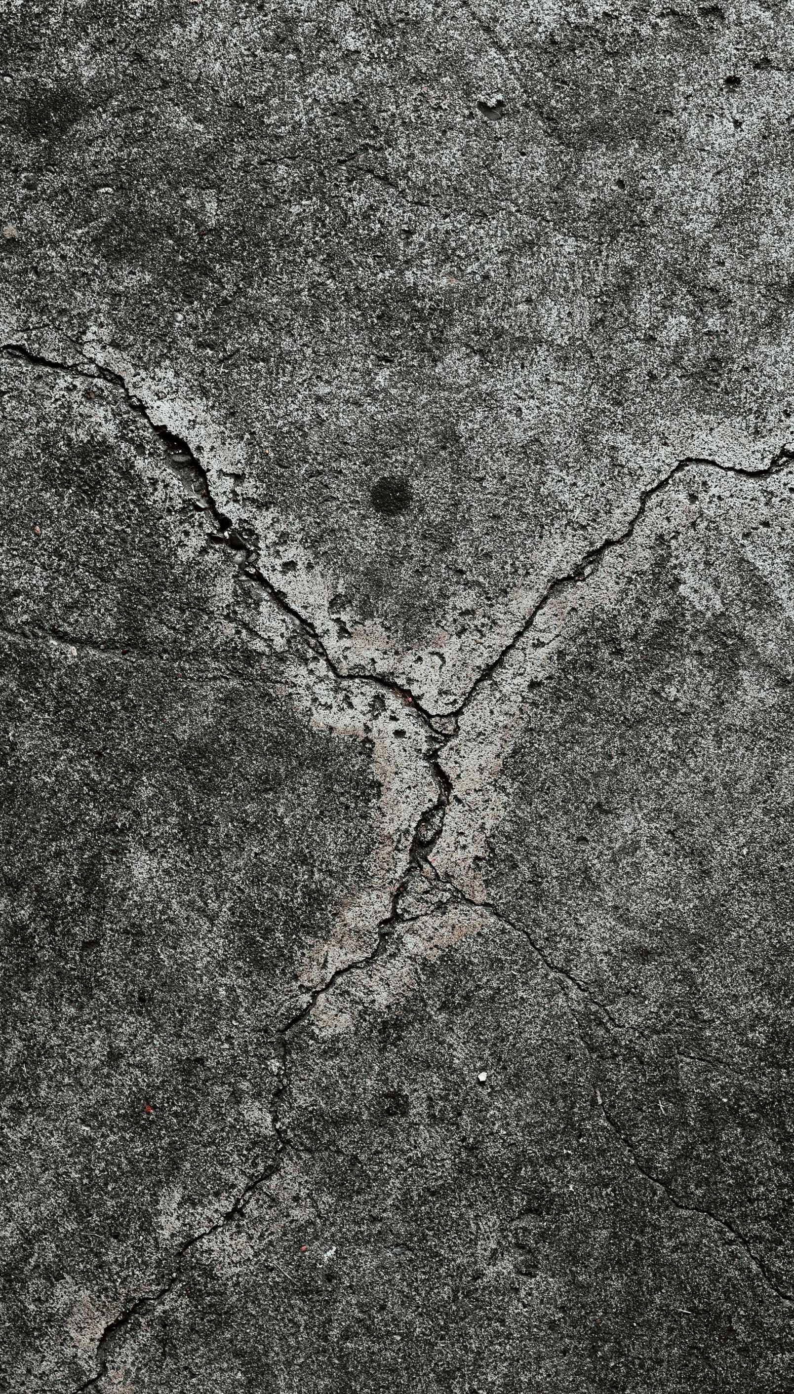 Cracked gray concrete surface with dark patches.