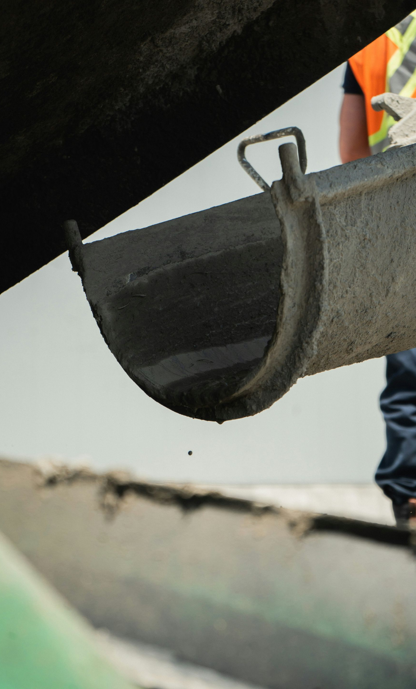 Close-up of a metal bucket hanging from a rope beside a worker in a reflective vest