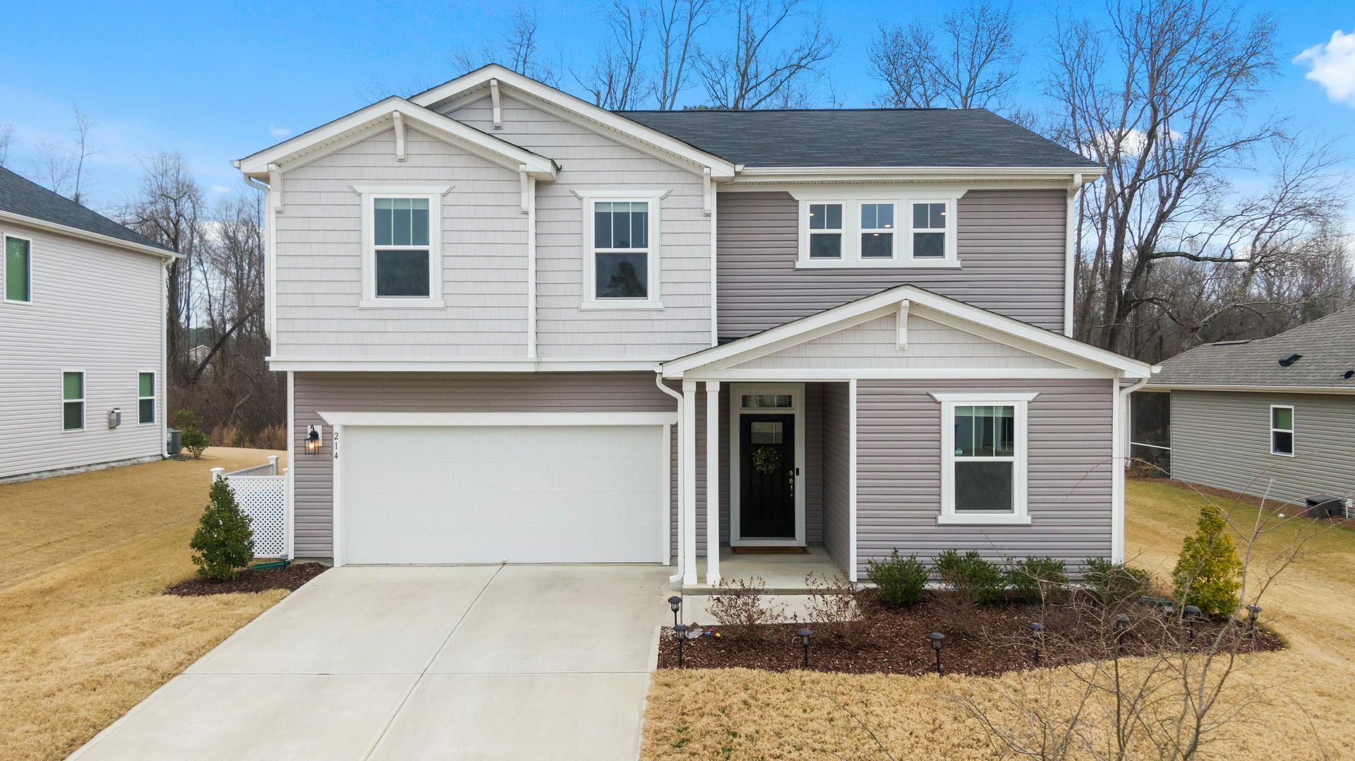 Two-story house with gray siding, white trim, attached garage, and small front porch.