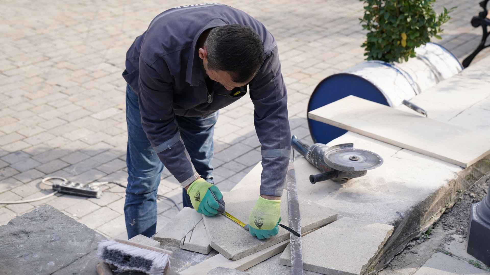 Worker cutting stone paving with an angle grinder outdoors