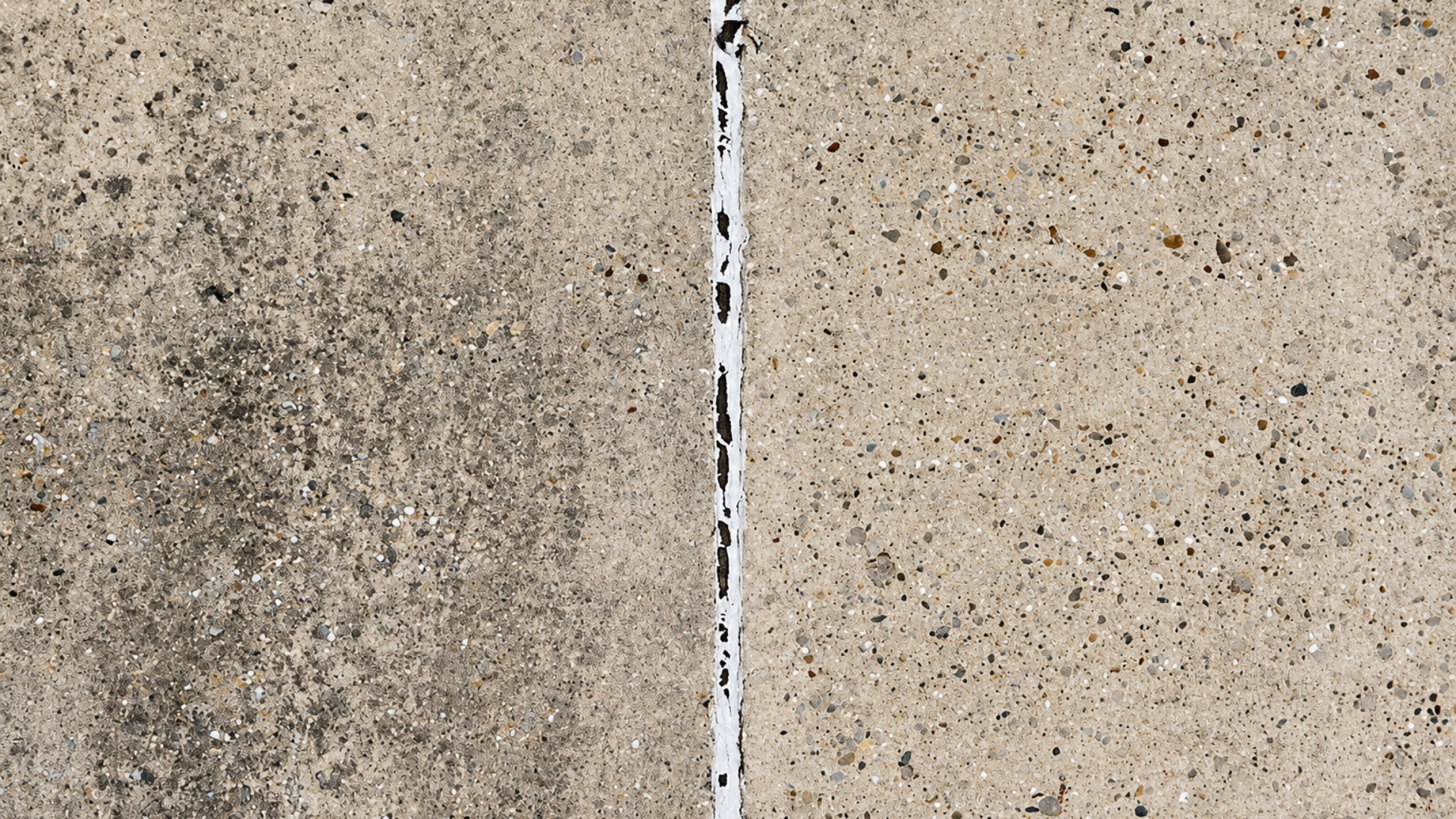 Close-up of two speckled concrete surfaces separated by a narrow vertical seam.