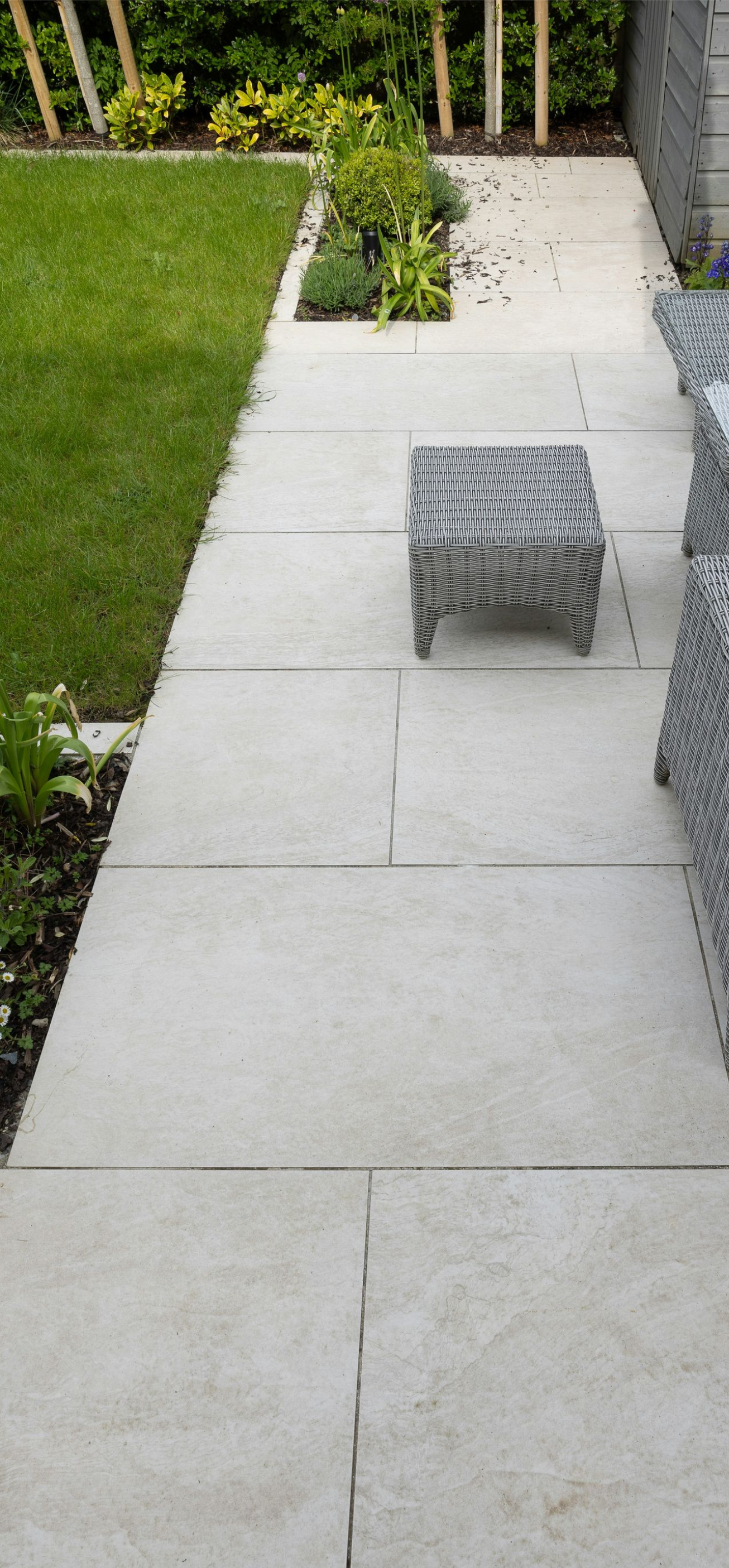 Backyard patio with light concrete pavers, a small woven ottoman, grass, and outdoor seating