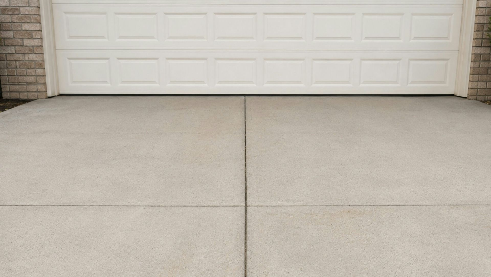 Empty concrete driveway in front of a white garage door