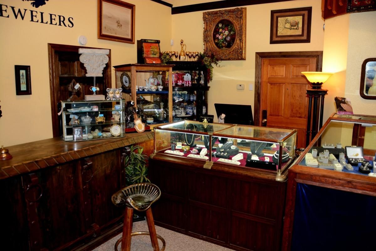 Jewelry store interior with display cases, wood counters, antique decor, and lighting.