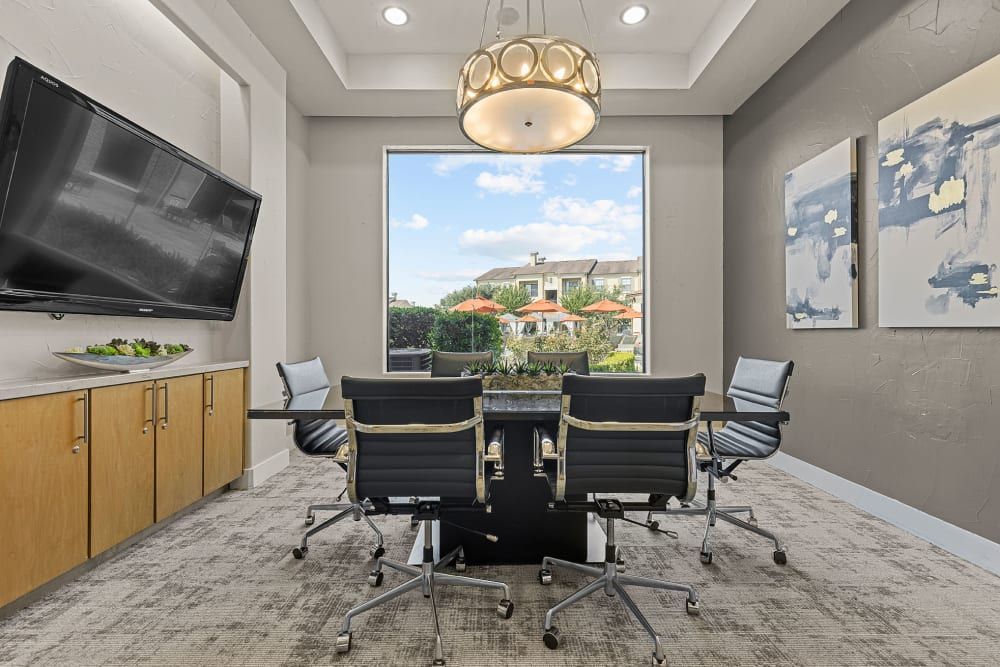 A conference room with a table and chairs and a large flat screen tv at Marquis at the Reserve in Katy, TX.