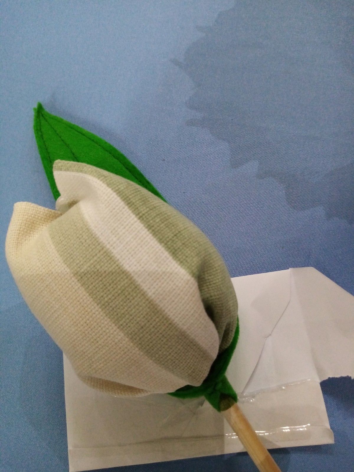 A flower with a green leaf is sitting on a piece of paper