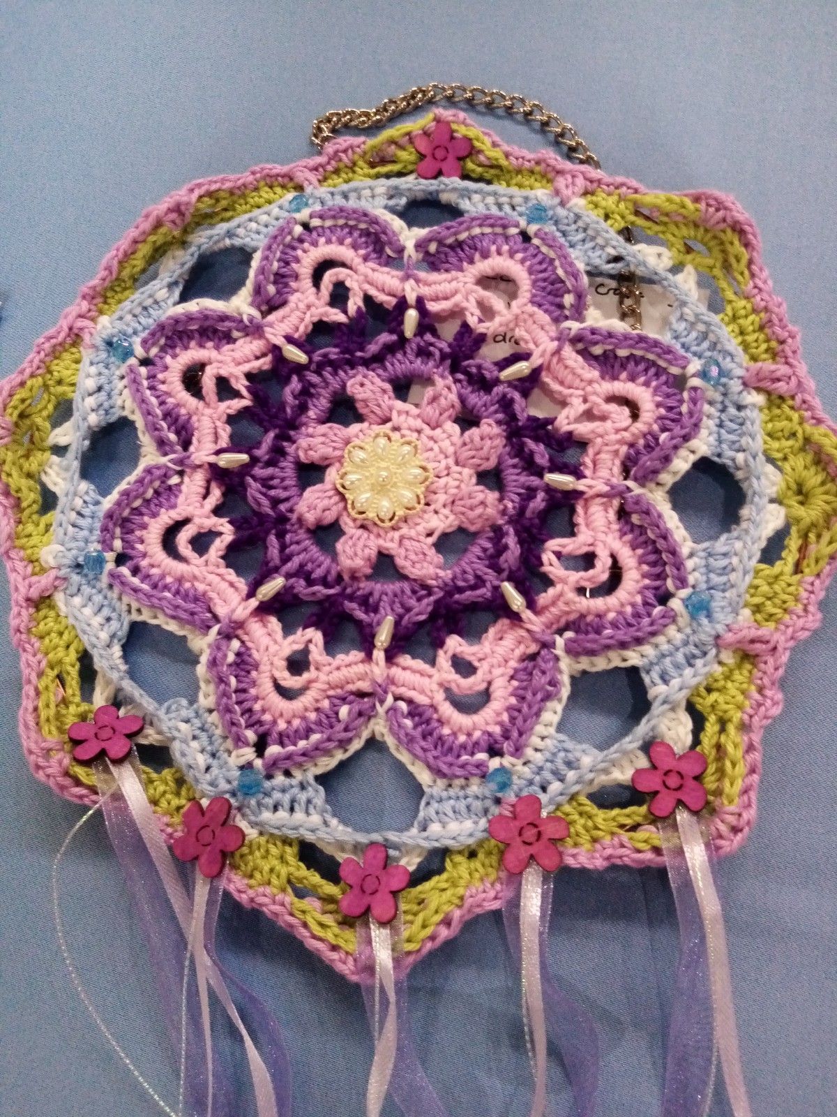 A crocheted dream catcher with pink and yellow flowers