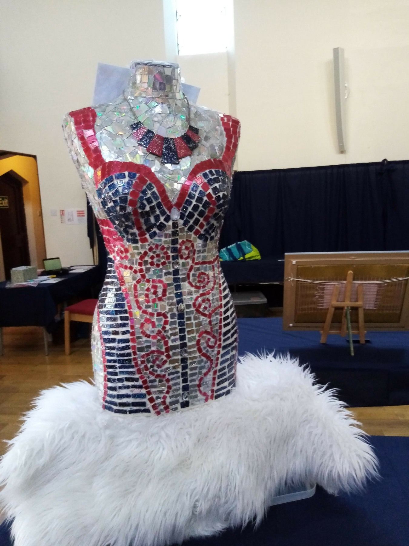 A mannequin is sitting on a white fur blanket
