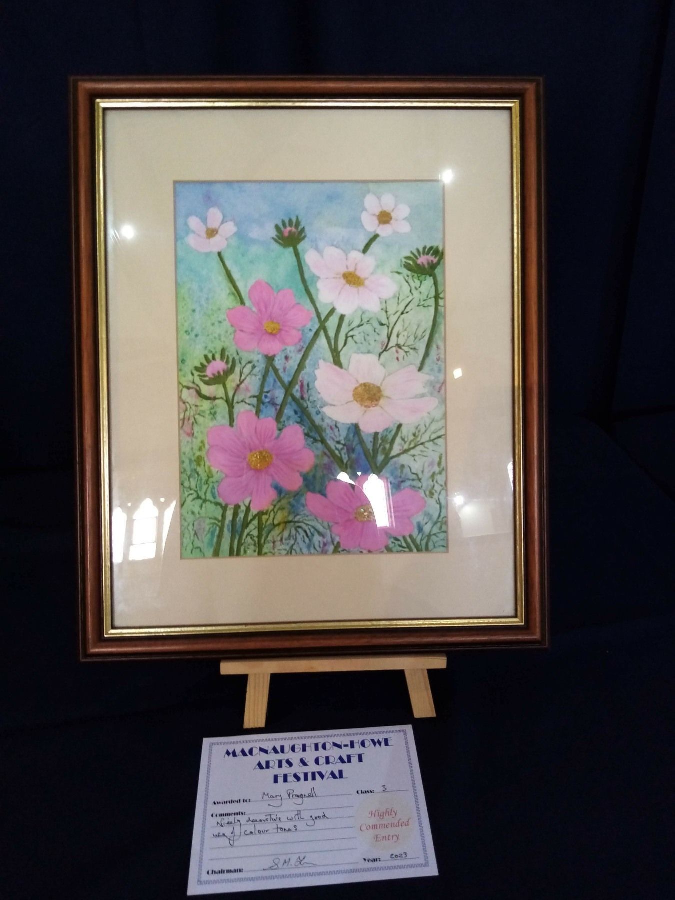 A framed picture of pink and white flowers on a blue background