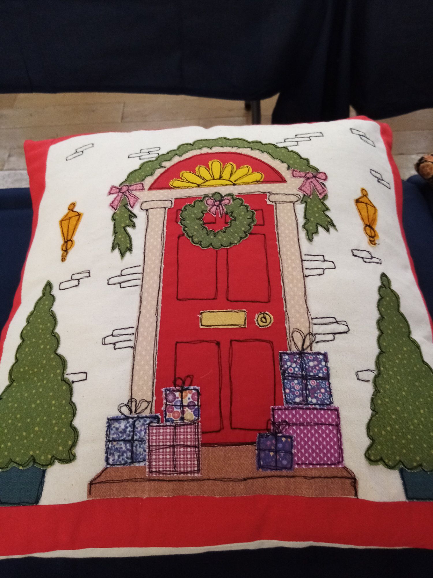 A christmas pillow with a red door and gifts on it