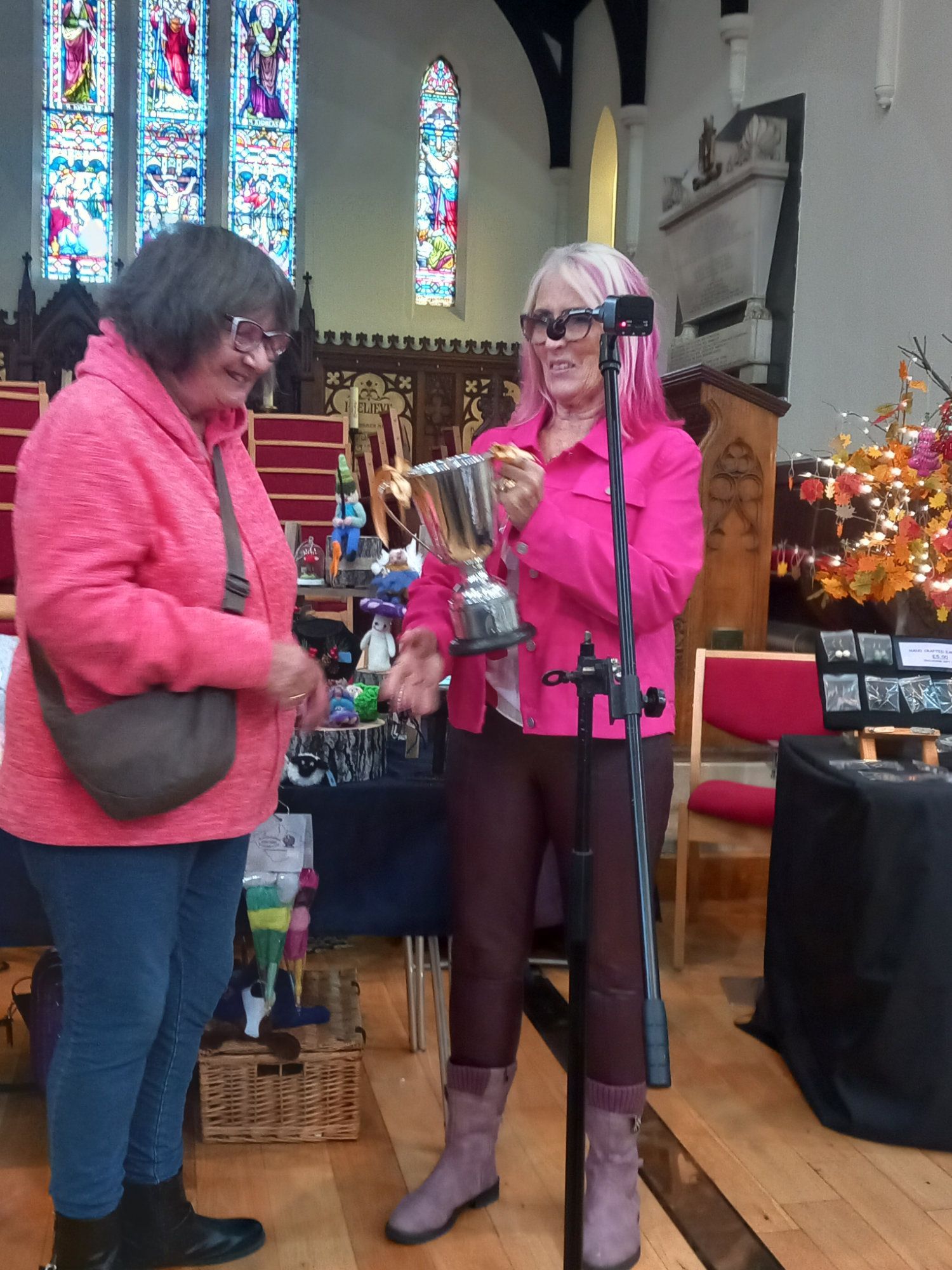 Two women standing in a church holding a trophy