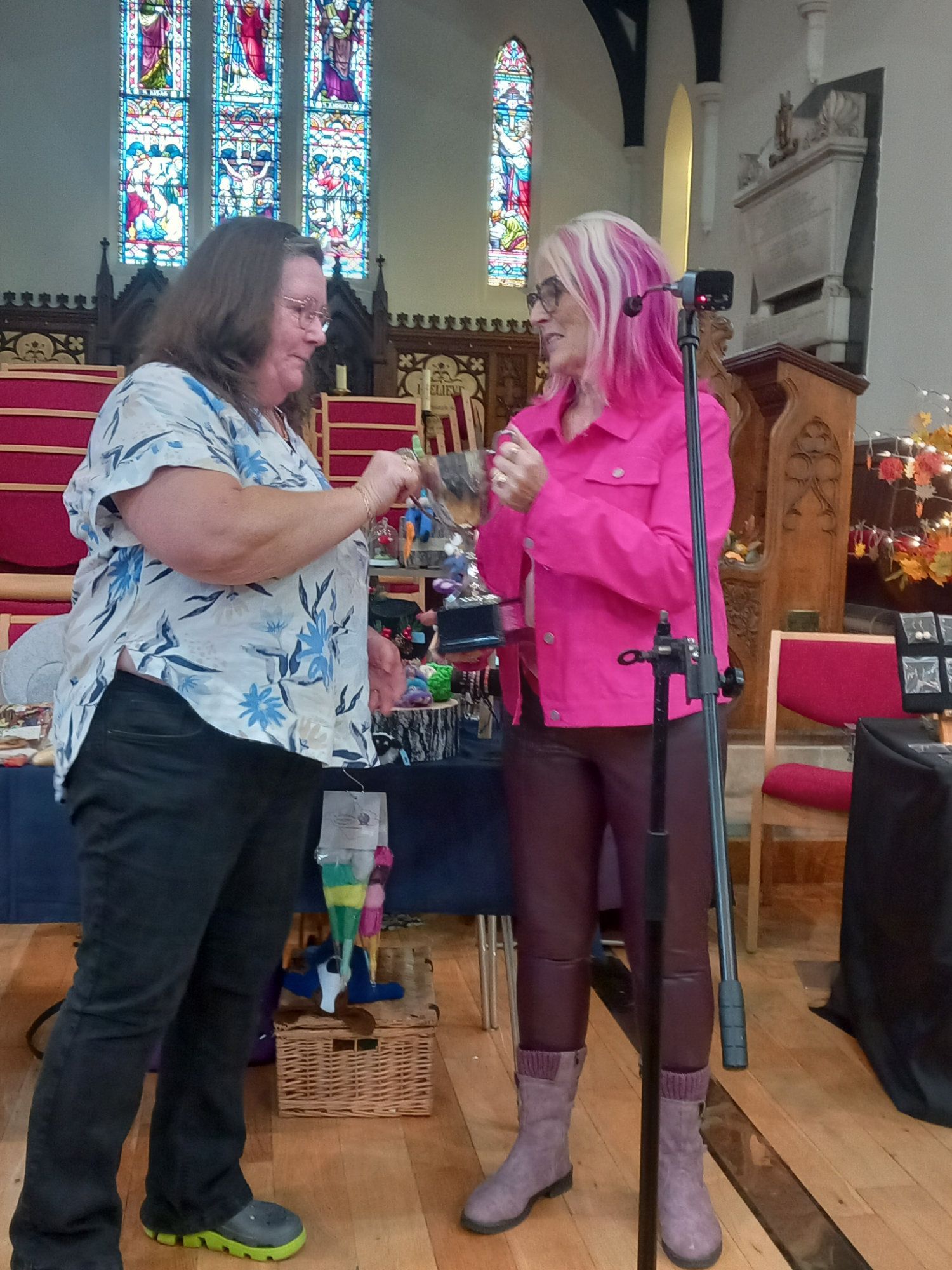 Two women are standing in front of a microphone in a church.