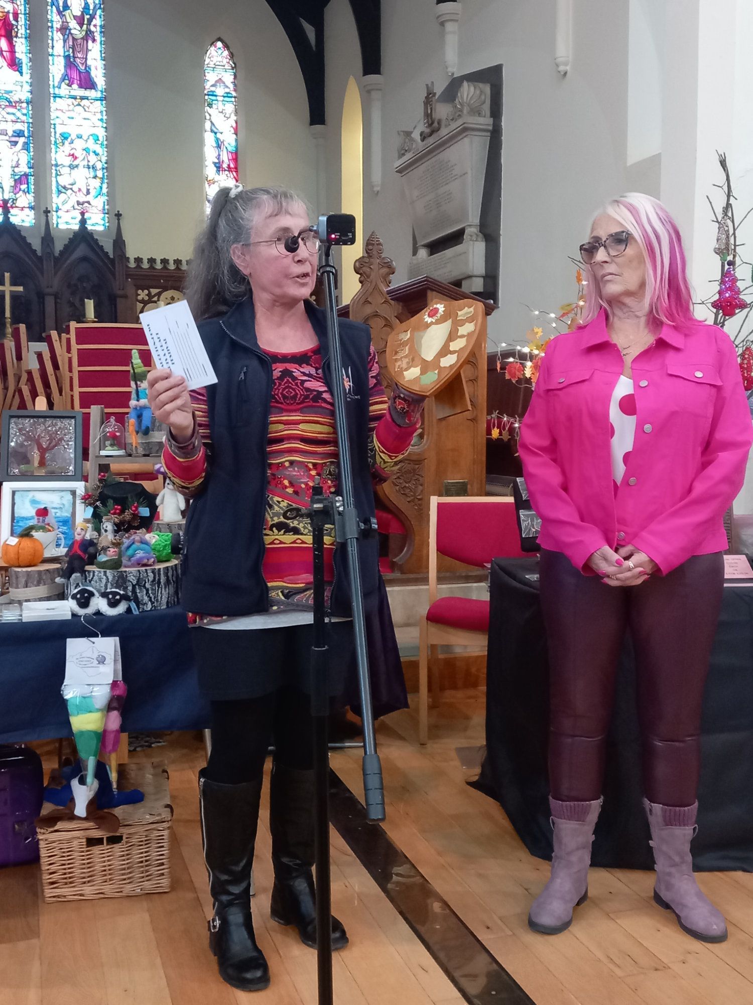 Two women standing in front of a microphone in a church