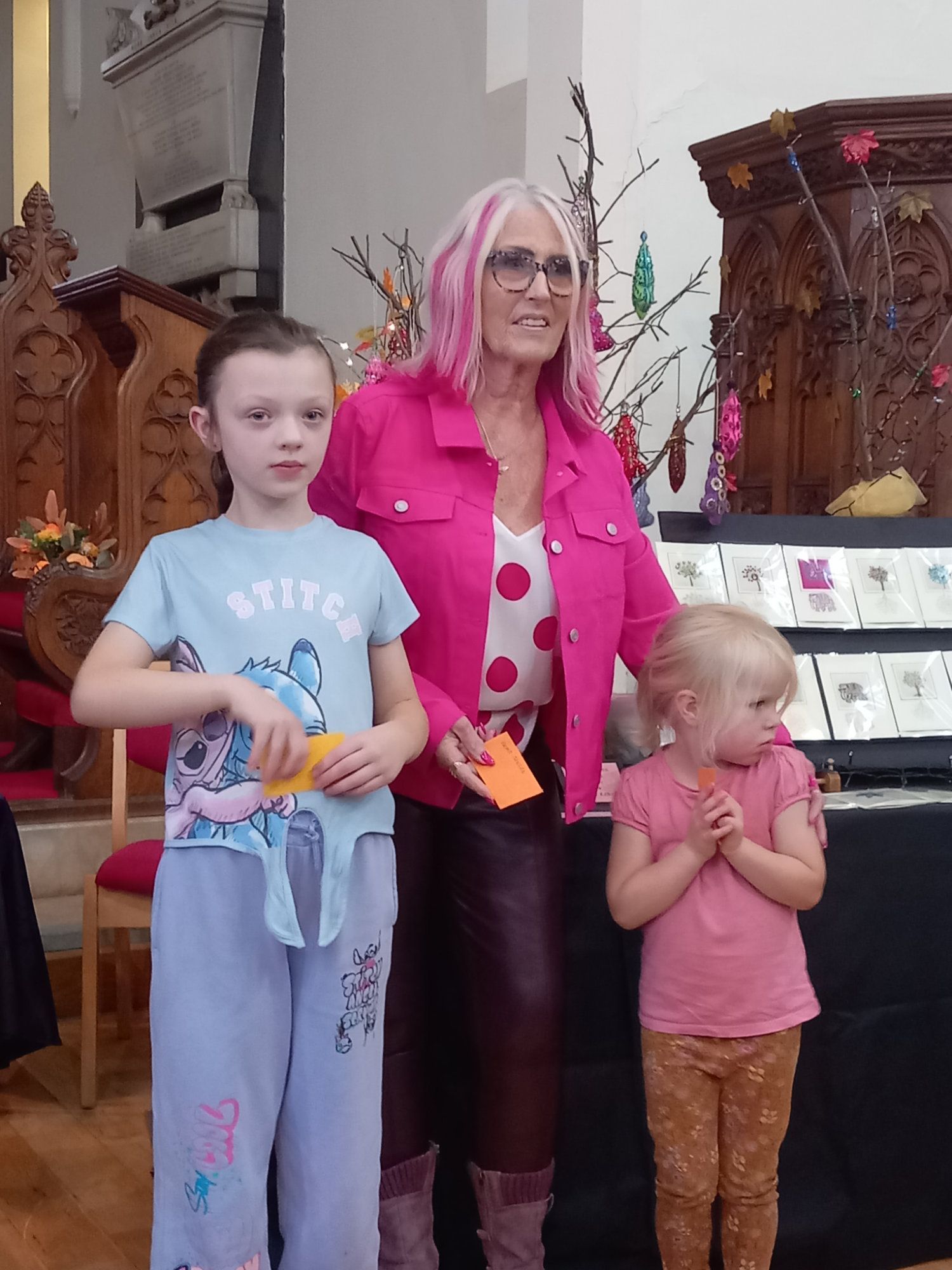 A woman with pink hair is standing next to two little girls