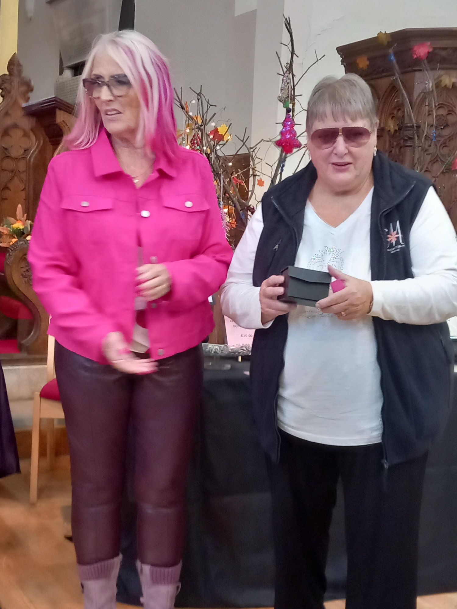 Two women are standing next to each other and one has pink hair